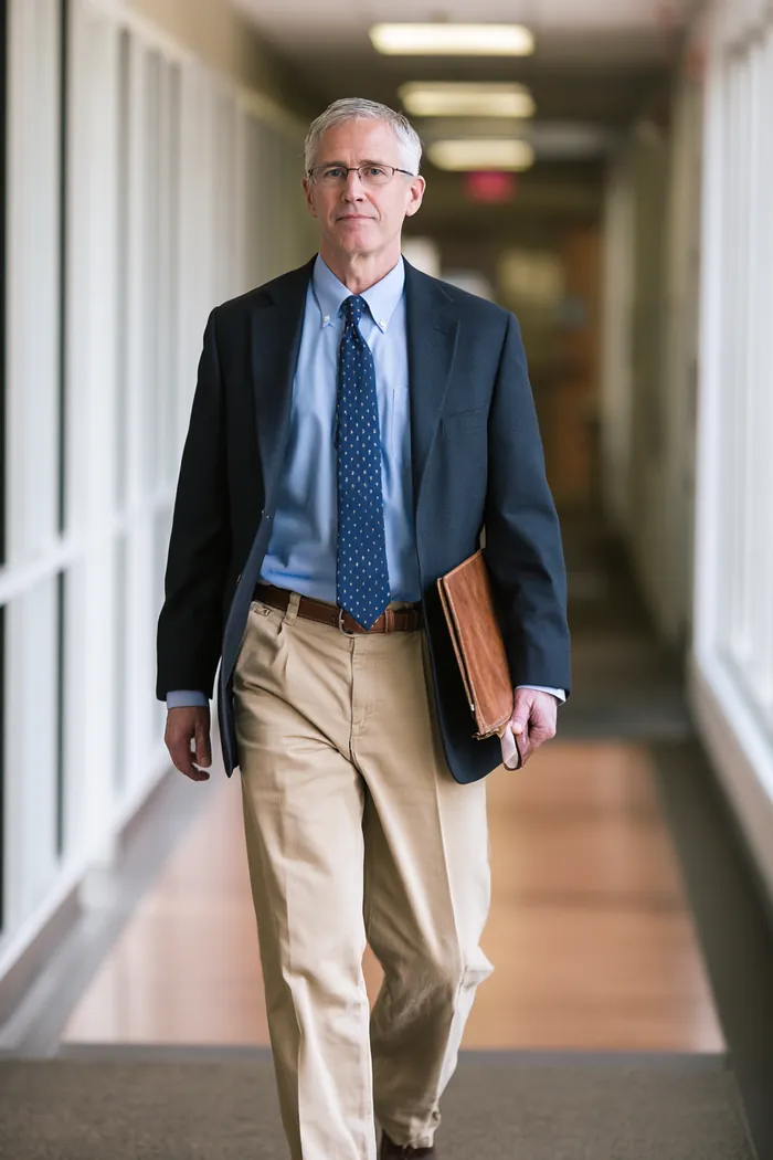 American loan specialist carrying a document folder through a bright office corridor